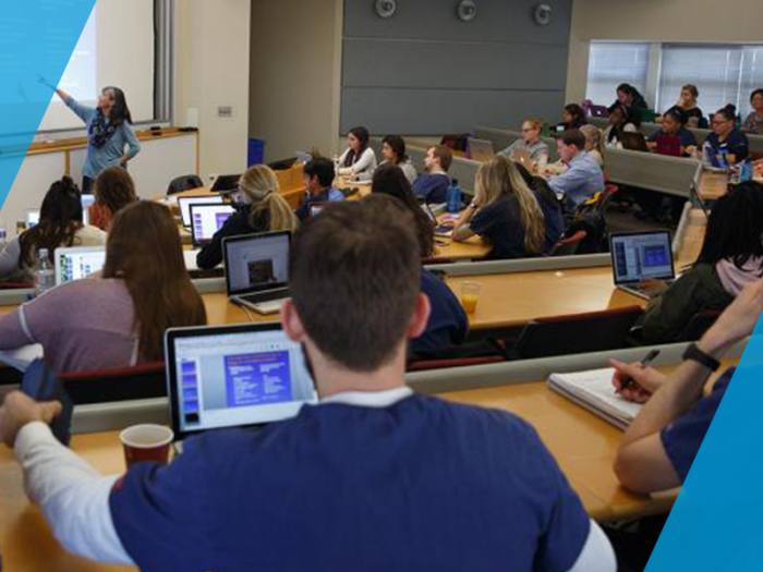 graduates with their laptops open listening to lecture