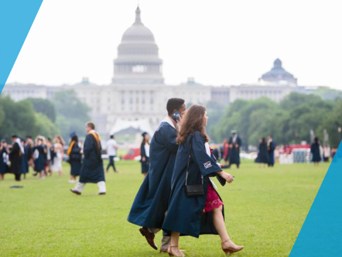 two GW graduates walk on the lawn with the capital building in the background